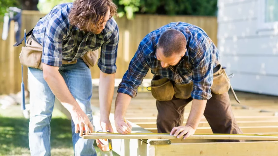 Two construction workers measuring dimensional lumber