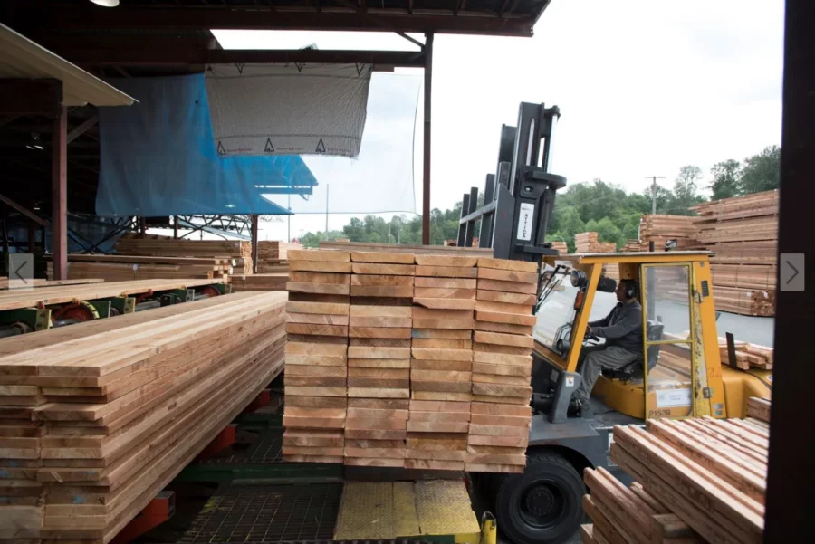 Stack of pressure treated lumber being brought indoors by a tractor at the lumber yard