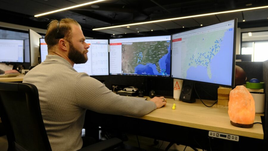 Male Lumber Trader working at a desk with three monitors