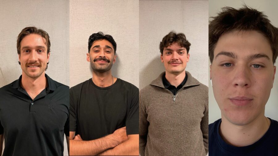 Four Lumber Traders posing in front of a wall showing off their moustaches