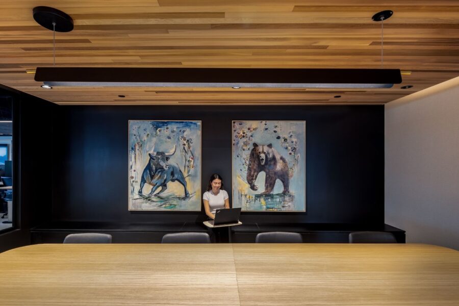 A woman sitting beneath paintings of a bull and a bear