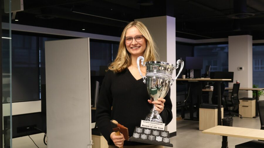 Woman standing in an office smiling holding a trophy