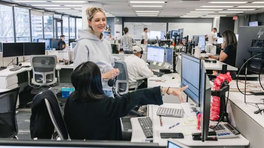 Two women talking in an office looking and pointing at a computer desktop